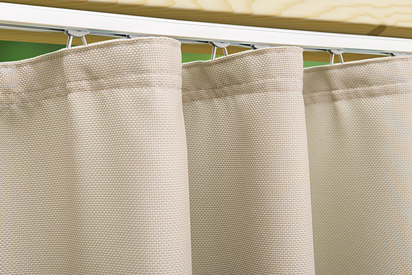 Handwerkliche Präzision: Maßgeschneiderte Details für einen eleganten und gleichmäßigen Wellenfall. Nahaufnahme des oberen Saums eines Outdoor-Vorhangs Structure mit Vorhangband für die Schienenmontage.