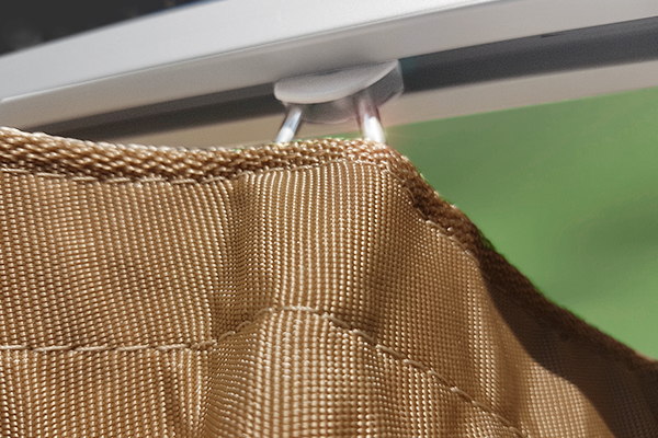 Hochwertige Verarbeitung: Reißfester Outdoor-Stoff und leichtgängiges Schienensystem im Detail. Detailansicht der Webstruktur eines wetterfesten Outdoor-Vorhangs in Beige mit Gleiter in einer Aluminium-Vorhangschiene.