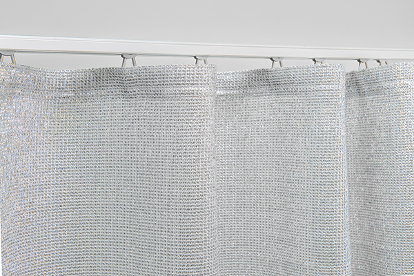 Material & Technik: Das hochreflektierende Coolish Netzgewebe im Detail. Detail der Coolish Netzstruktur und Aufhängung mit Gleitern in einer Aluminium-Vorhangschiene vor weißem Hintergrund.