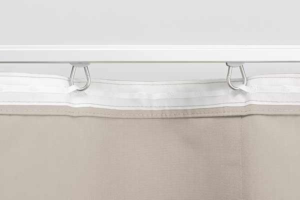 Stabile Edelstahl-Laufrollen für leichtes Gleiten in der Vorhangschienen für den Gentle Outdoor-Vorhang. Detailaufnahme der Rückseite eines beigen Outdoor-Vorhangs Gentle mit weißem Gardinenband und Laufrollen in der Aluminium-Vorhangschiene.