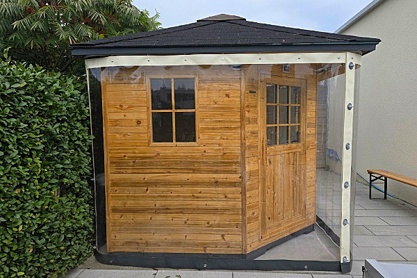 Regendicht und flexibel: Transparente Schiebeplane schützt Holzsauna im Garten Regendicht und flexibel: Transparente Schiebeplane schützt Holzsauna im Garten