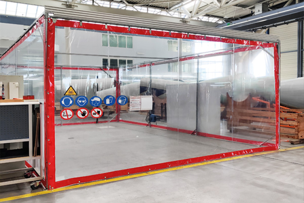 Einhausung für eine Schleifkabine aus transparenter Plane seitlich verschiebbar. Einhausung aus transparenter PVC-Plane an Montageschienen befestigt